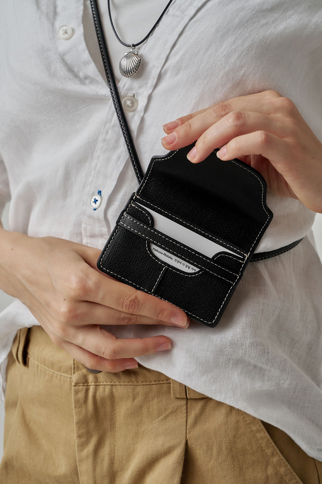 Black MIULIN 1st Anniversary Edition wallet bag showing compact design with zip closure and stylish leather exterior.