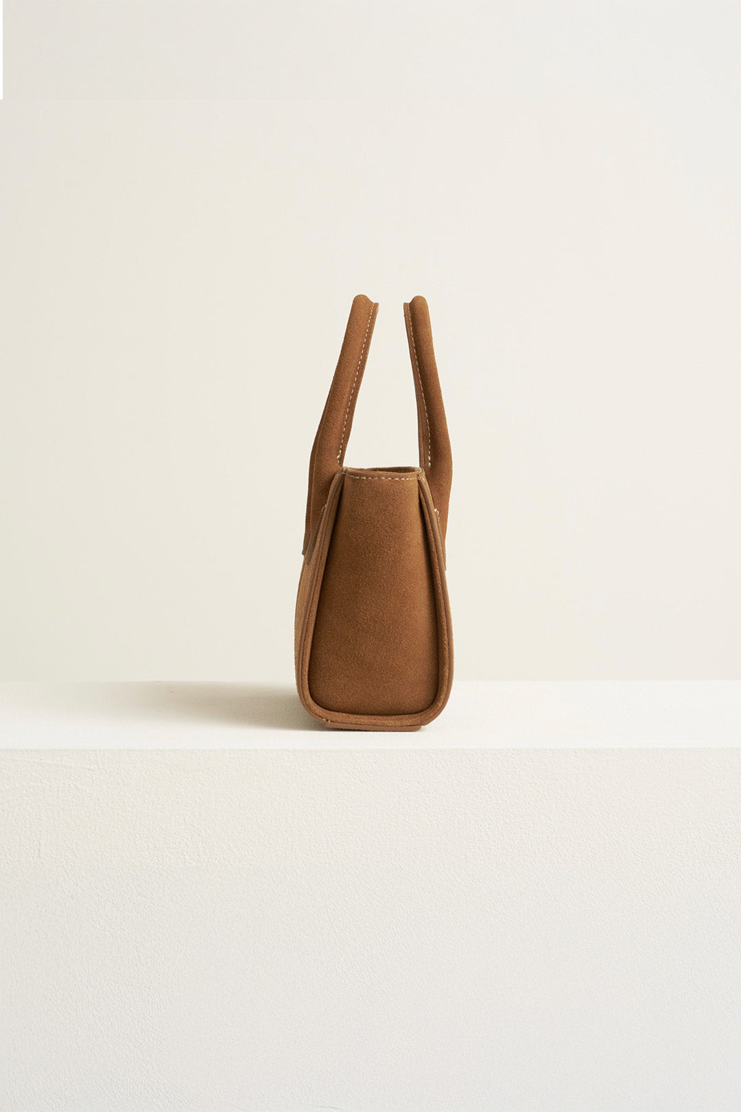 Small MIULIN Brunir suede tote bag with top handles and minimalist design, showcasing soft brown suede material.