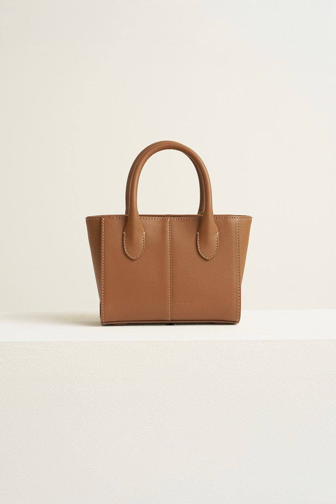 Small MIULIN Camille leather tote bag with structured design and top handles, showcasing its elegant craftsmanship.