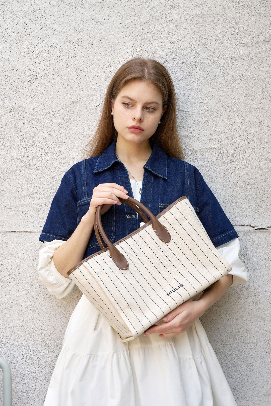 Large cream-colored canvas tote bag with striped design from MIULIN, showing sturdy handles and spacious interior.