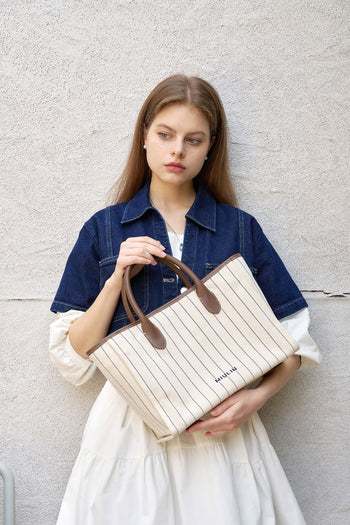 Large cream-colored canvas tote bag with striped design from MIULIN, showing sturdy handles and spacious interior.
