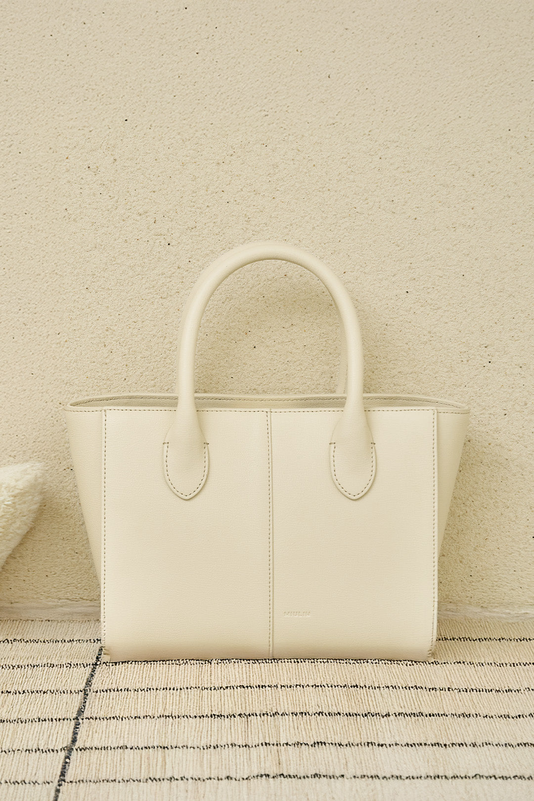Small Ivoire leather bag by MIULIN, featuring a sleek design with top handles and smooth texture, perfect for stylish everyday use.