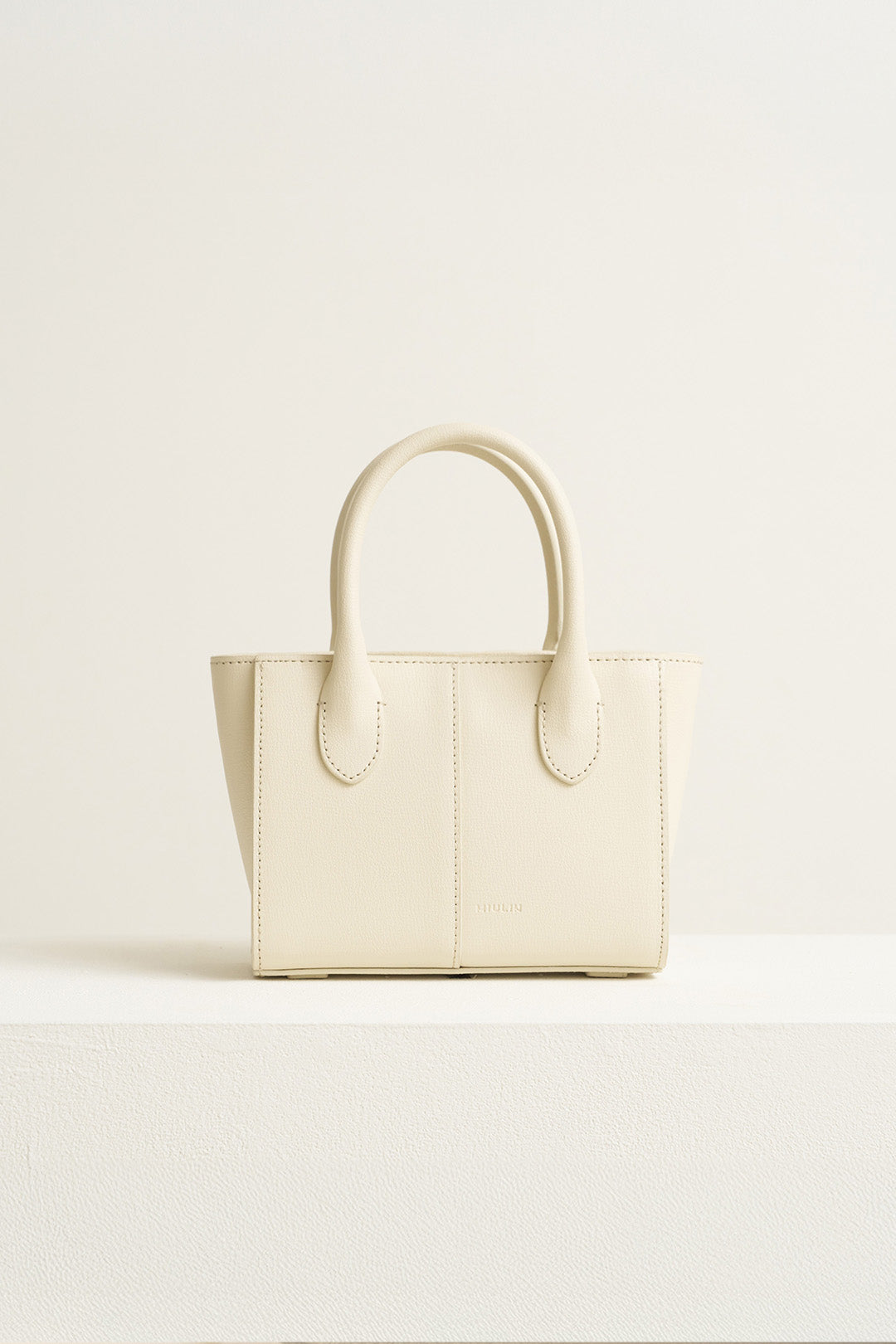 Small Ivoire leather bag by MIULIN featuring a sleek design with top handles and subtle stitching.