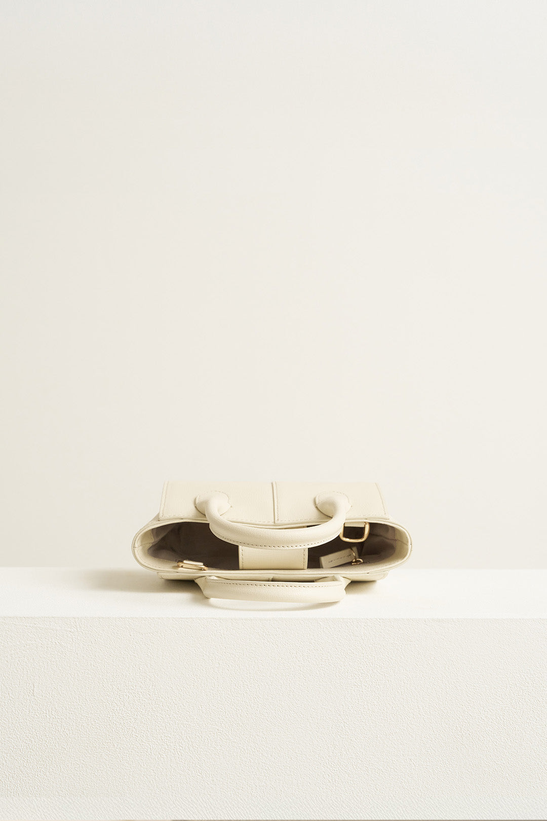 Small Ivoire leather tote bag by MIULIN, featuring a sleek design, sturdy handles, and smooth Ivory-colored leather.