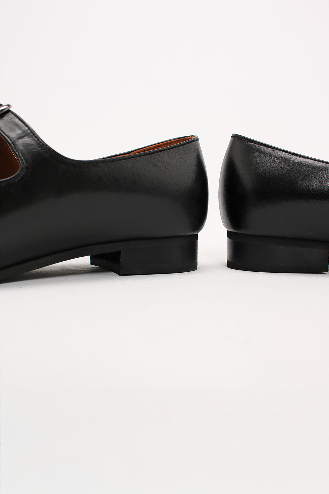 Black Nora strap flat shoes by Finoacinque featuring a sleek design and comfortable flat sole, shown from a side angle.