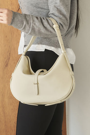 Ivory Shellie Hobo Bag by MIULIN with soft leather, slouchy design, and adjustable shoulder strap, shown from the side.