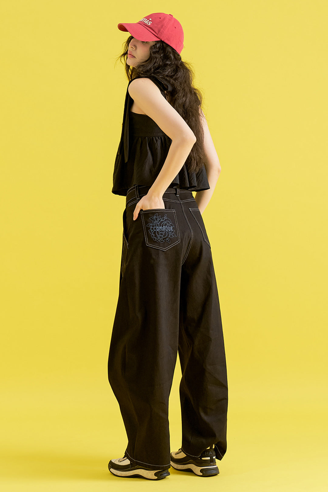 Black denim pants with chrysanthemum knot detail from CCOMAQUE, showcasing stylish bottoms with unique floral accents.