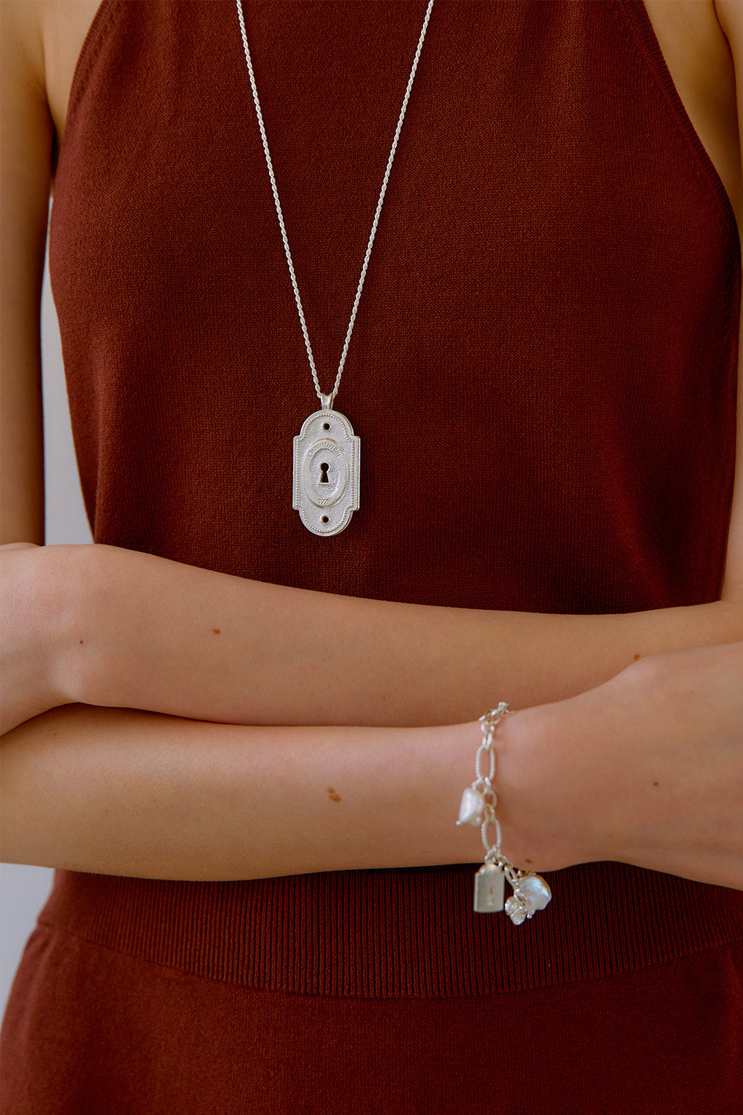 Silver lock pendant necklace by Chambriller featuring a sleek design, worn on a chain with a shiny silver finish.