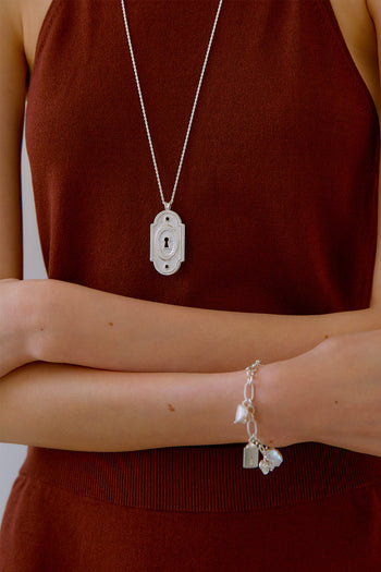 Silver lock pendant necklace by Chambriller featuring a sleek silver chain and a prominent lock charm.