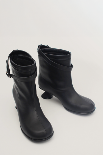Black Uhjeo Hourglass Middle Heel Strap Boots by Finoacinque featuring ankle-high design and stylish strap details.