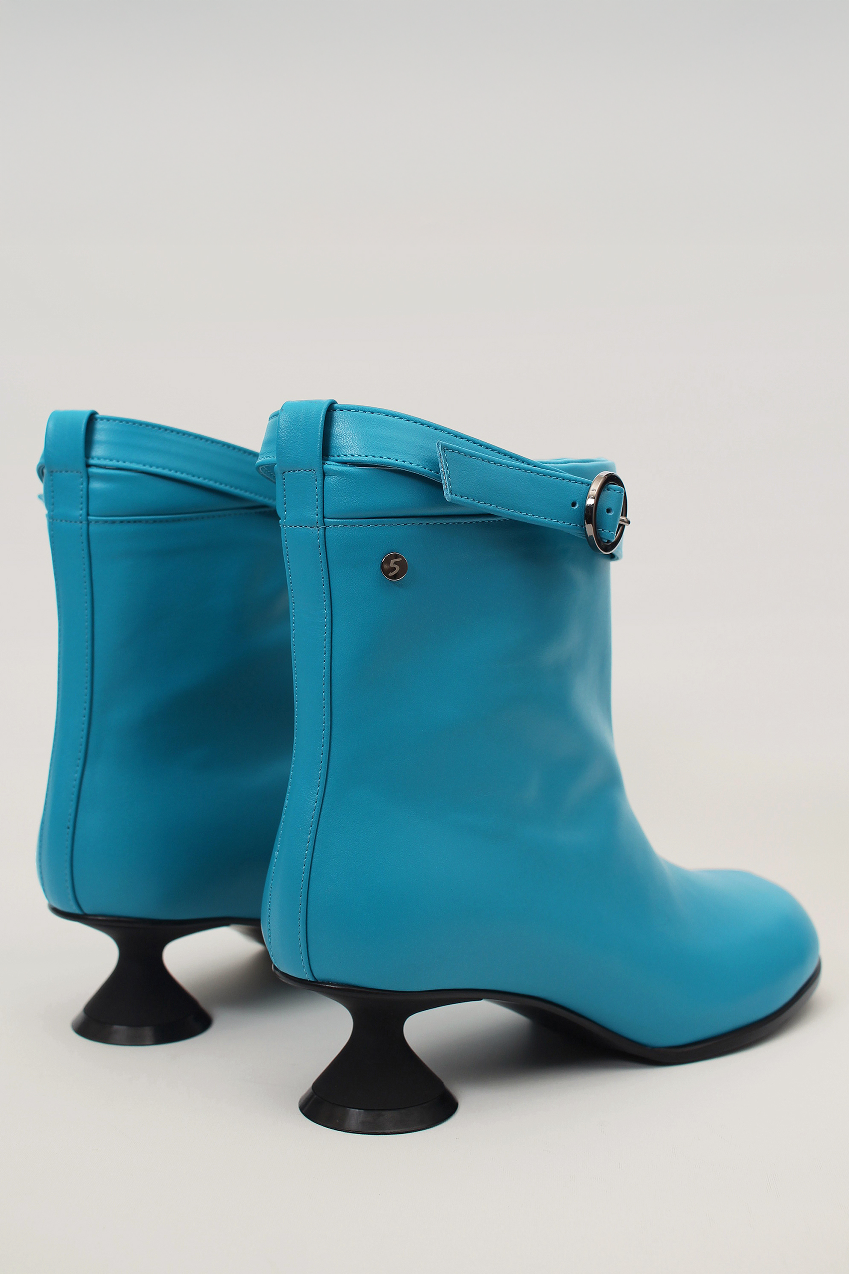 Finoacinque Uhjeo blue hourglass middle heel strap boots showing sleek design and stylish ankle straps on a white background.