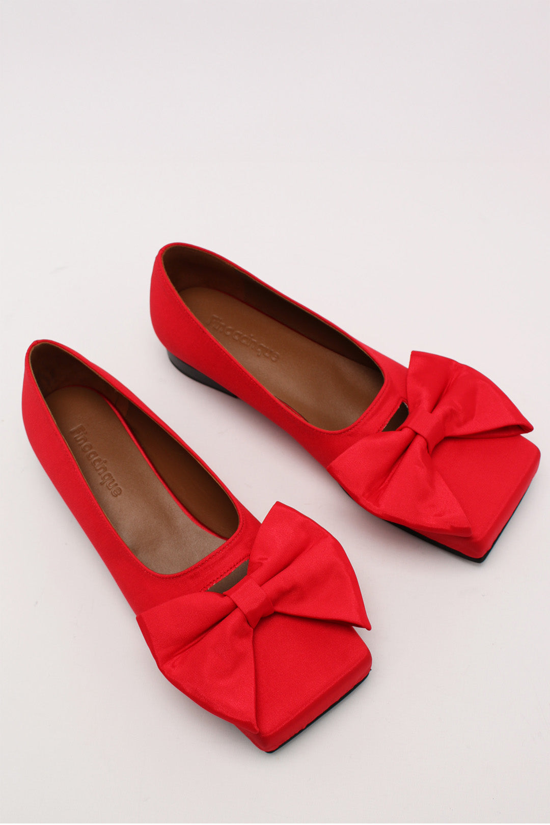 Red satin flat shoes with a bow detail from Finoacinque, featuring a classic ballerina style for elegant everyday wear.