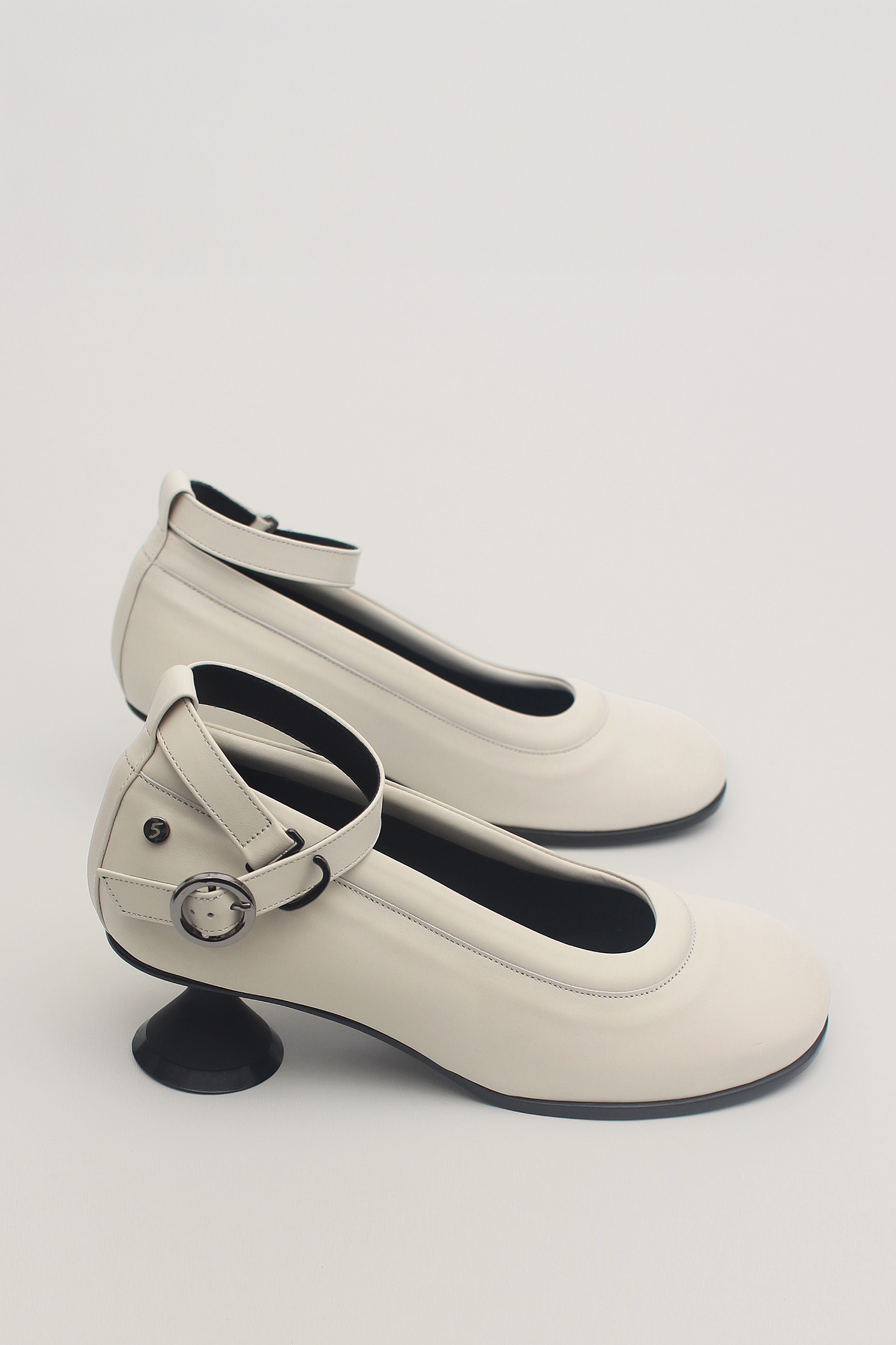 Finoacinque Uhjeo white hourglass middle heel strap pumps showing sleek design and stylish ankle strap detail.