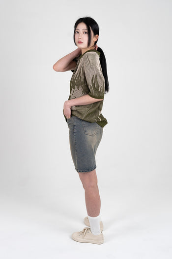 IOEDLE Meteor Shower Knit Khaki shirt displayed on a hanger, showcasing its casual knit design and khaki color.