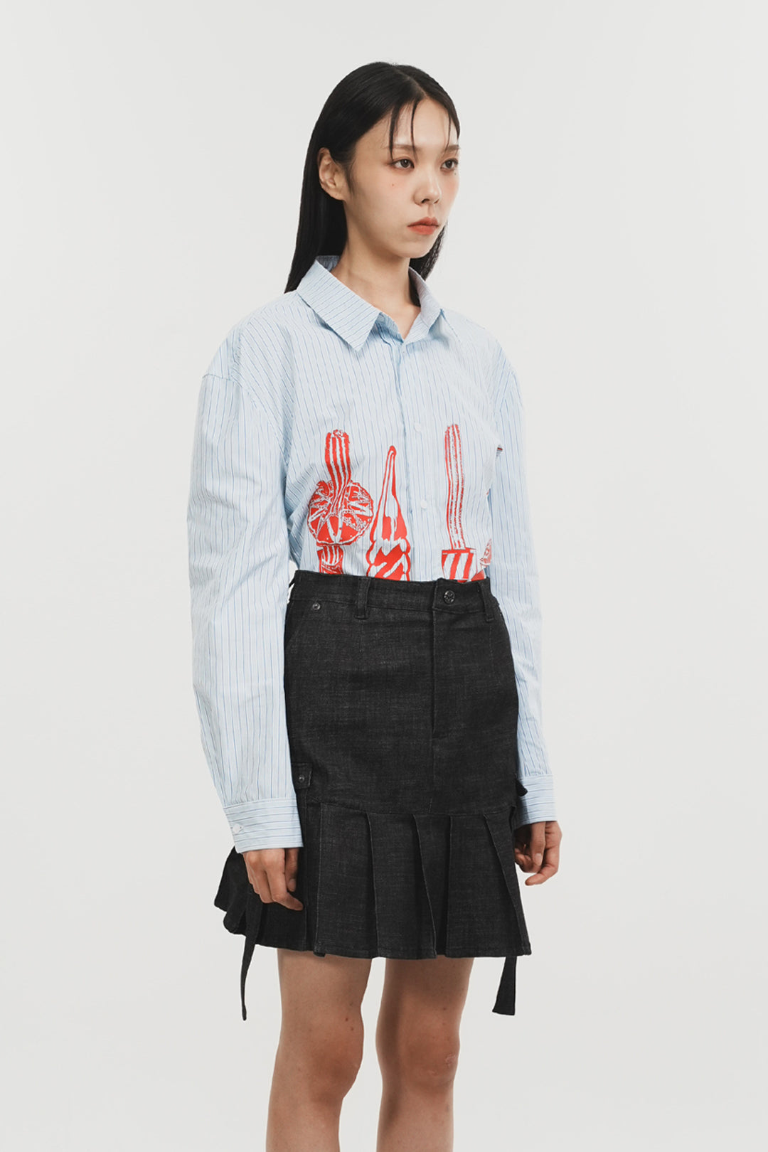 Charcoal denim pleats skirt by Phenomenon Seeper, shown from the side with a high waist and flowing pleated design.
