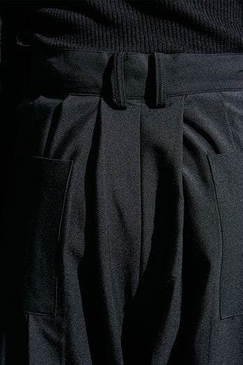 Black wide pleated pants from Reculer, featuring a relaxed fit and pleated design, shown on a model.