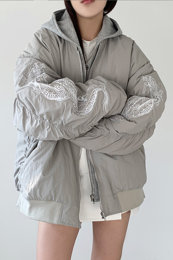 White bomber jacket with beige and grey embroidery featuring a dragon design, by TM3, shown on a hanger.