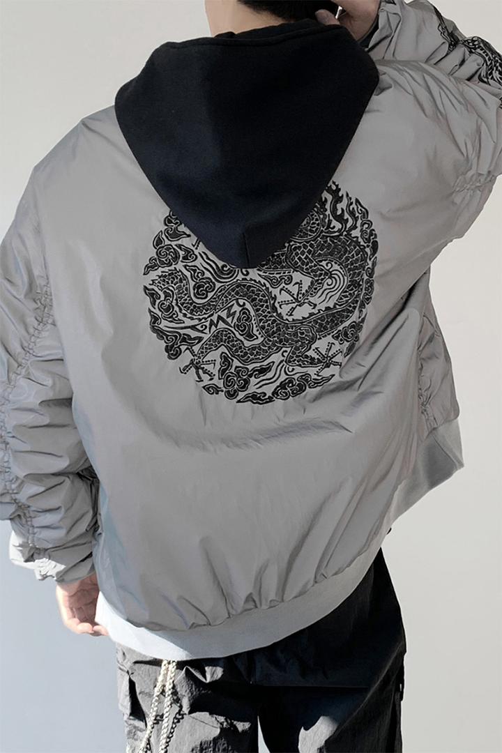 Black TM3 bomber jacket with dragon embroidery, grey fabric, reflective accents, and a zip-up front.