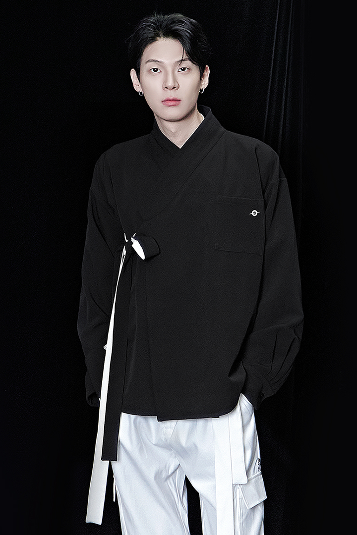 Black oversized shirt from TM3, relaxed fit, long sleeves, and classic collar, displayed on a hanger.